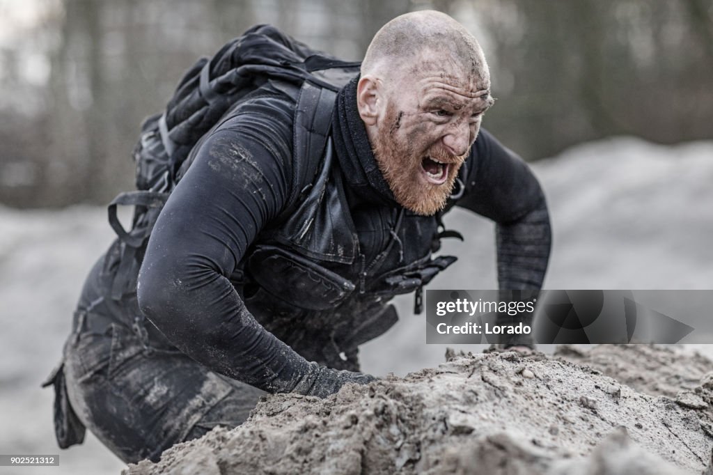 Redhead shaved male military member training hard on a sand hill run