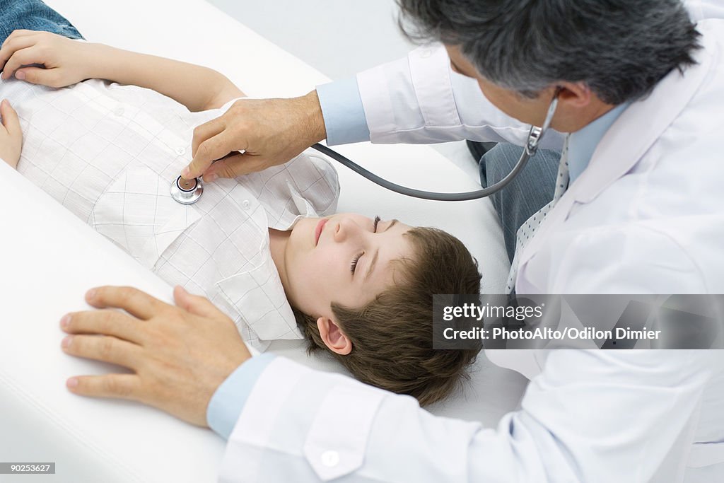 Doctor listening to young patient's heart, high angle view