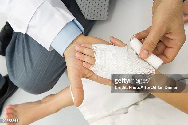 doctor wrapping a patient's hand in gauze, high angle view - brandde stockfoto's en -beelden
