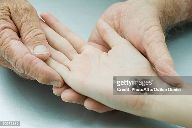 man holding young person's hand, palm facing up, cropped view - palmistry hand stock pictures, royalty-free photos & images