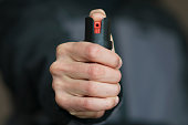 Man holding pepper spray (tear gas) in his hand. Self-defense. Blur background, close up