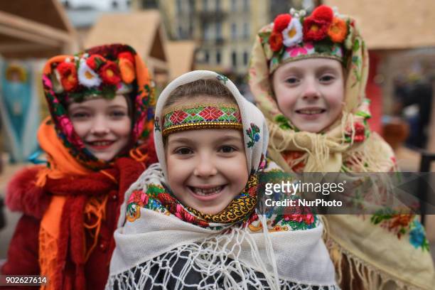 Three young girls wear traditional folk dresses from different regions during the Christmas Stars Parade that take place in Lviv on the second day of...