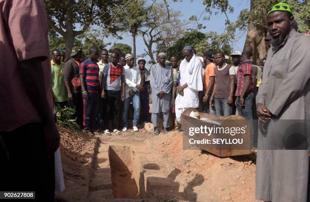 Men pray next to a coffin during a burial in a cemetery in the regional capital Ziguinchor, southern Senegal on January 7, 2018 following an attack...