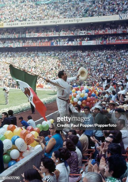 An exhuberant local man encourages the crowd by waving a Mexican flag and a sombero in the Azteca Stadium in Mexico City during the opening ceremony...