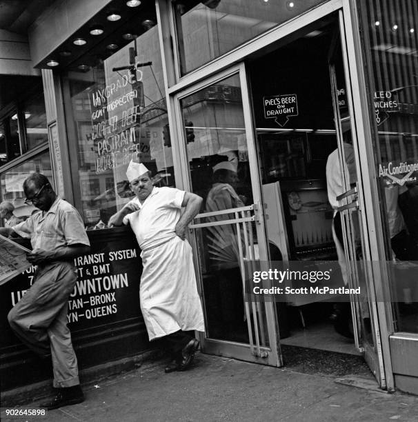 Delicatessen owner taking a break, stands outside his store in Times Square, New York.