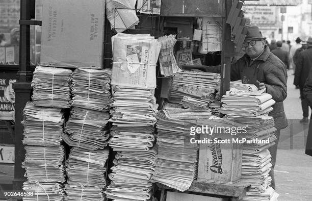 Stacks of New York Times newspapers sit next to a man's newsstand on 42nd street in Times Square, New York.
