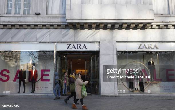 Pedestrians walk past a display window offering post-Christmas sales outside a Zara clothing store on January 8, 2018 in Berlin, Germany. Many German...