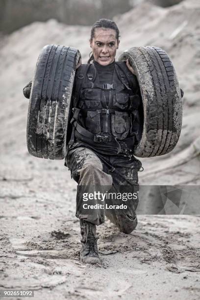 beautiful brunette female military member during training in muddy sand outdoors - military training stock pictures, royalty-free photos & images