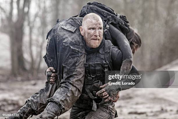 macho shaven headed redhead male military swat security anti terror member carrying female team member during operations - damsels in distress stock pictures, royalty-free photos & images