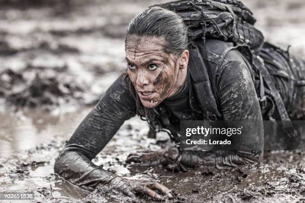 schöne brünette weiblichen militärischen swat sicherheit anti-terror-agent während der operationen in schlammigen sand krabbeln - sports training drill stock-fotos und bilder