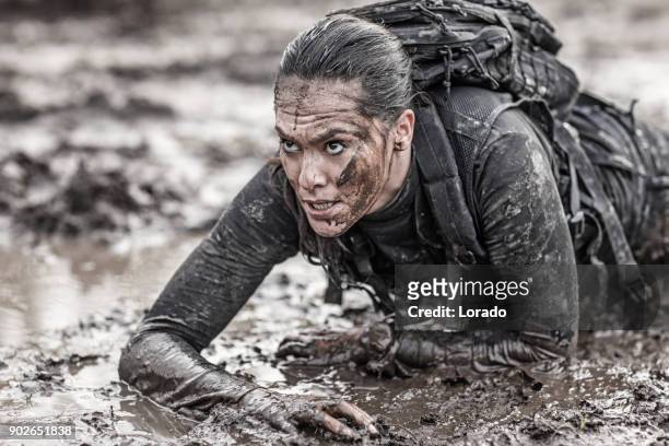 bella bruna militare swat sicurezza agente antiterrorismo strisciare durante le operazioni in sabbia fangosa - brunette woman foto e immagini stock