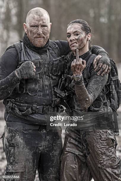 roodharige mannelijke en brunette vrouwelijke militairen swat beveiliging anti-terreur duo tijdens operaties in buiten modderige instelling - counter terrorism stockfoto's en -beelden