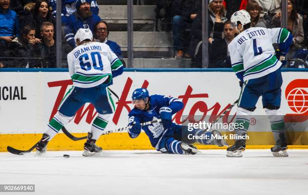 Mitchell Marner of the Toronto Maple Leafs plays the puck against Markus Granlund and Michael Del Zotto of the Vancouver Canucks during the second...