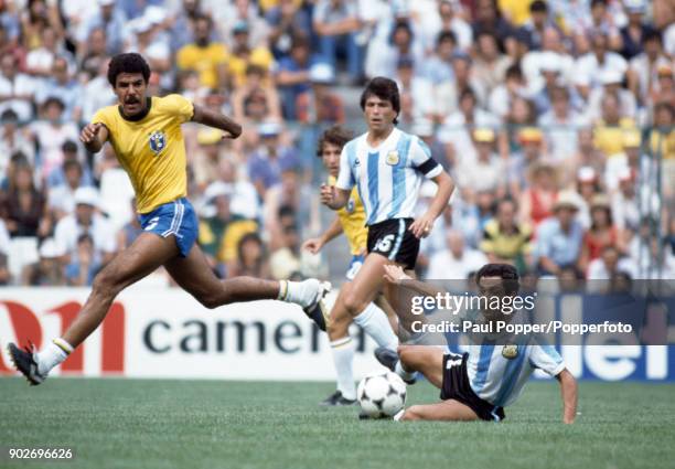 Osvaldo Ardiles of Argentina slides in to take the ball from Toninho Cerezo of Brazil during the FIFA World Cup match between Argentina and Brazil at...