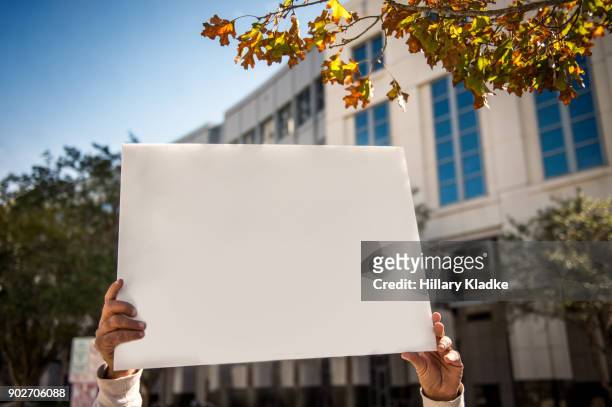 protestor holding up blank sign - placard stockfoto's en -beelden