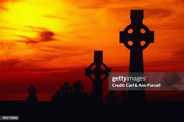 celtic crosses silhouetted at sunset - ann purcell stockfoto's en -beelden