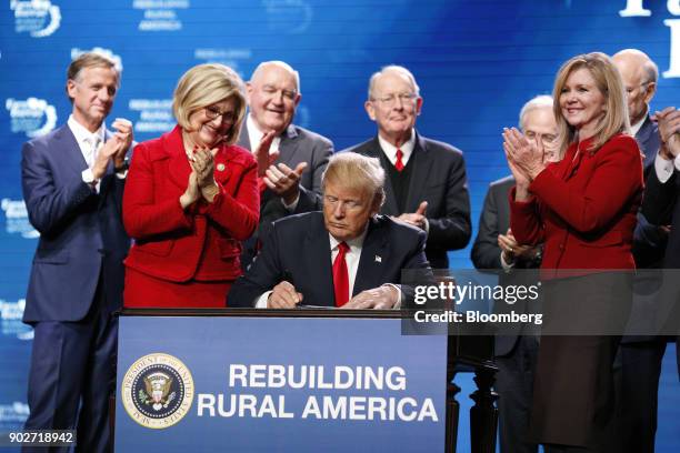 President Donald Trump signs an executive order, expanding rural broadband access to towers on federal lands, during the annual American Farm Bureau...