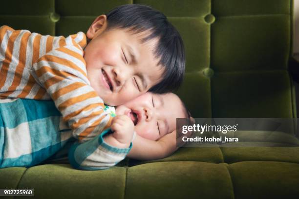 boy hugging baby on sofa - baby brother stock pictures, royalty-free photos & images