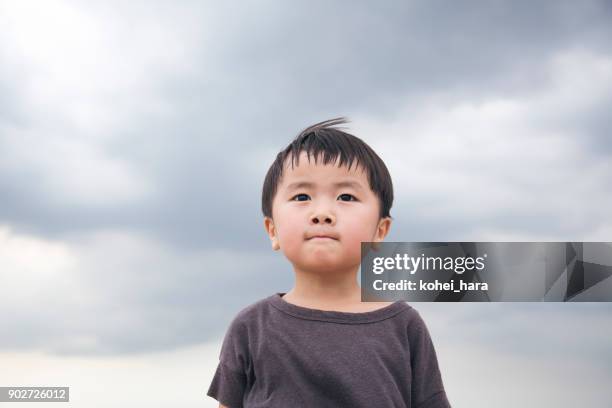 boy standing under a cloudy sky - determination kids stock pictures, royalty-free photos & images