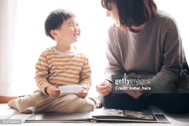 madre e hijo sonriendo juntos al mismo tiempo que el álbum de fotos - album fotos fotografías e imágenes de stock