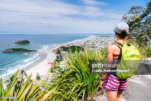 a woman stops on the trail overlooking mount maunganui beach - berg maunganui stockfoto's en -beelden