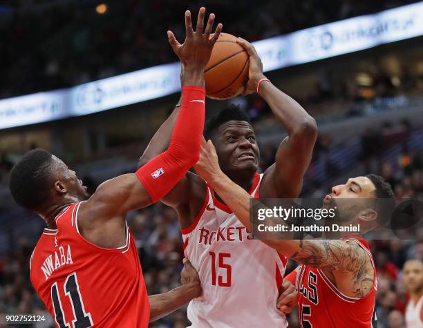 Clint Capela of the Houston Rockets drives between David Nwaba and Denzel Valentine of the Chicago Bulls at the United Center on January 8, 2018 in...