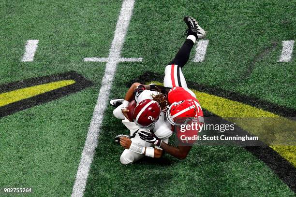 Jalen Hurts of the Alabama Crimson Tide is tackled by Davin Bellamy of the Georgia Bulldogs on a run during the second quarter in the CFP National...