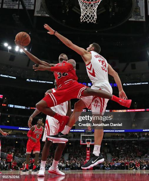 Kris Dunn of the Chicago Bulls drives between Ryan Anderson and Clint Capela of the Houston Rockets at the United Center on January 8, 2018 in...