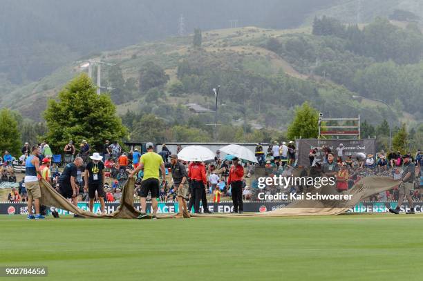 Groundsmen pull the covers over the wicket as rain delays play during the second match in the One Day International series between New Zealand and...