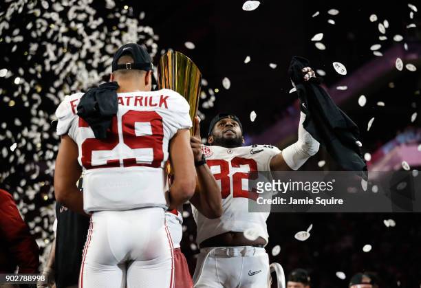 Rashaan Evans of the Alabama Crimson Tide holds the trophy while celebrating with his team after defeating the Georgia Bulldogs in overtime to win...