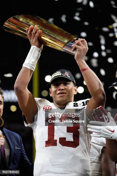 Tua Tagovailoa of the Alabama Crimson Tide holds the trophy while celebrating with his team after defeating the Georgia Bulldogs in overtime to win...