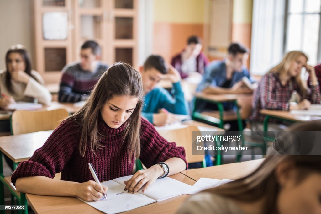 Female high school student writing a test in the classroom.