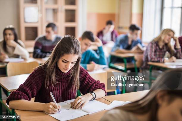 kvinnliga high school-student som skriver ett test i klassrummet. - exam bildbanksfoton och bilder