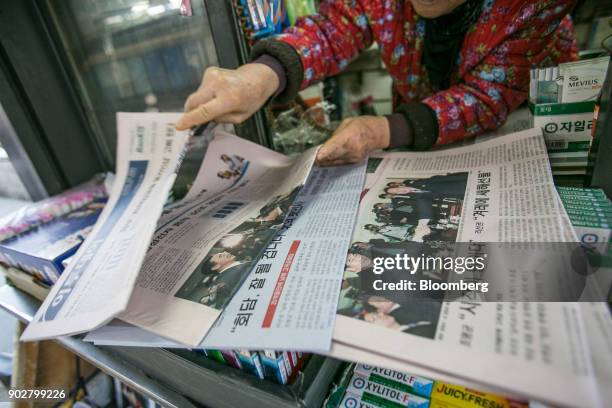 Vendor sorts through newspapers featuring photographs of Cho Myoung-gyon, South Korea's unification minister, left, shaking hands with Ri Son Gwon,...