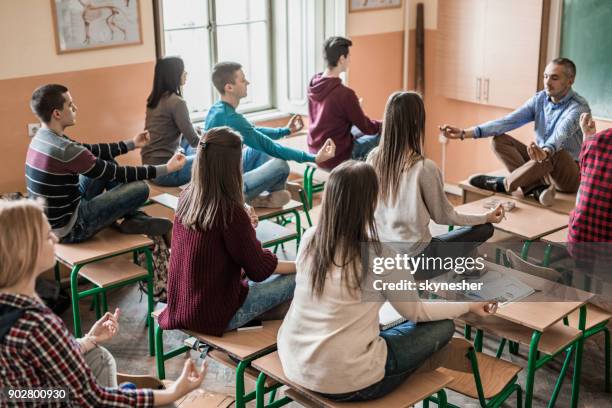 group of students with their professor meditating in the classroom. - teenager yoga stock pictures, royalty-free photos & images