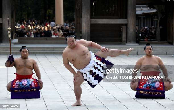 Sumo grand champion or "yokozuna", Kisenosato , performs a ring-entering ceremony beside tachimochi, or sword carrier Shohozan and tsuyuharai, or dew...