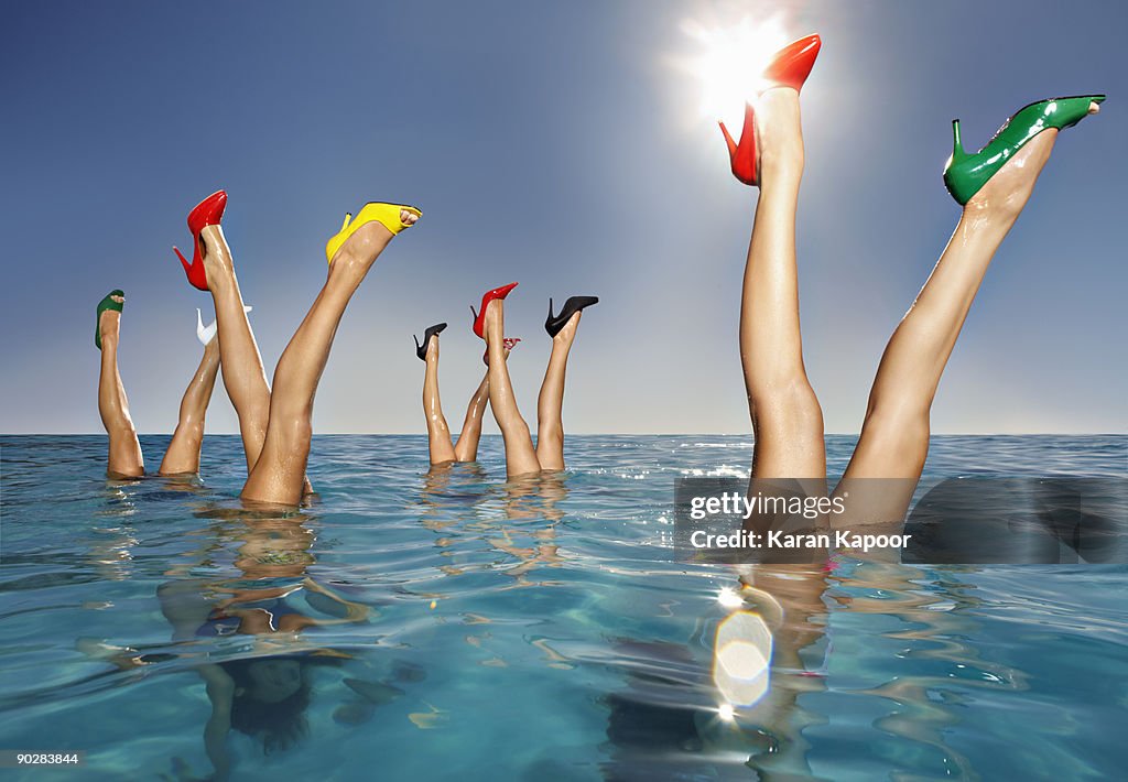 Group of legs portruding out of infinity pool