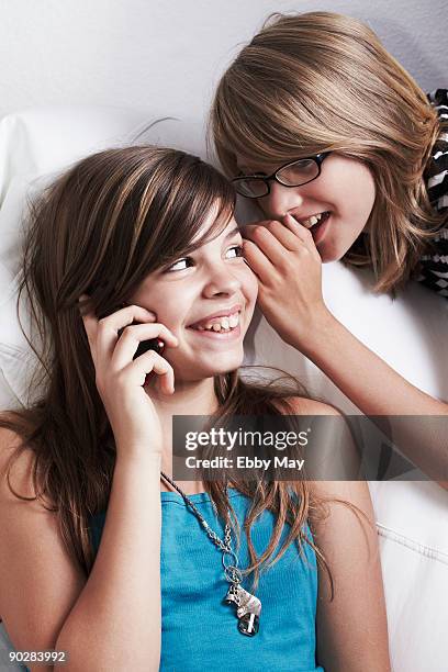 girl whispering in girl's ear while using mobile  - bad mergentheim stock pictures, royalty-free photos & images