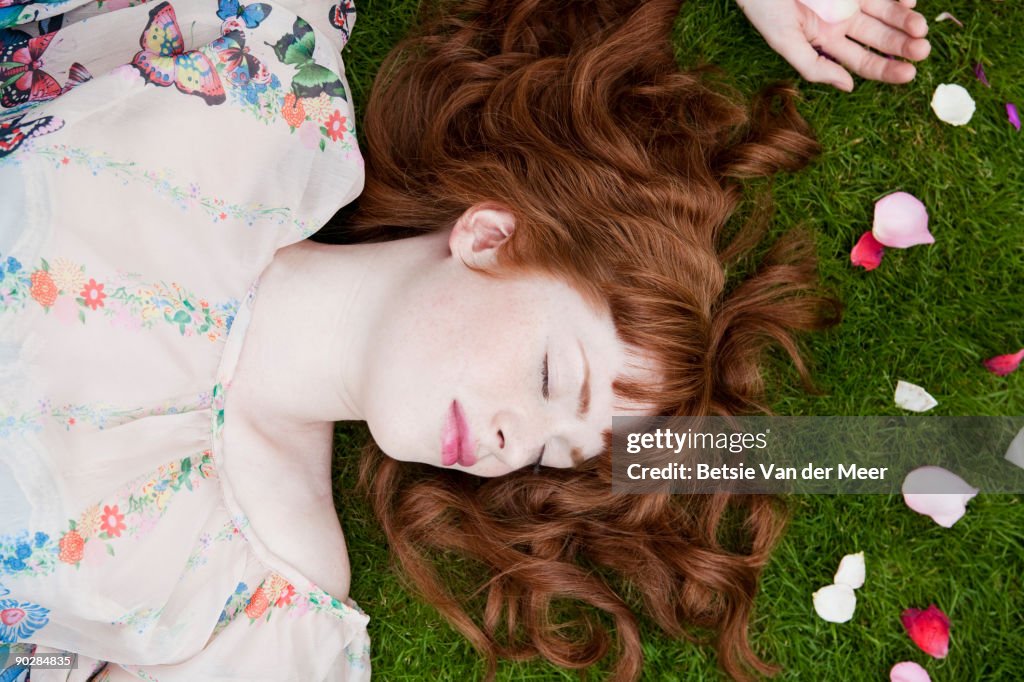 Woman sleeping, surrounded by flowerpedals.