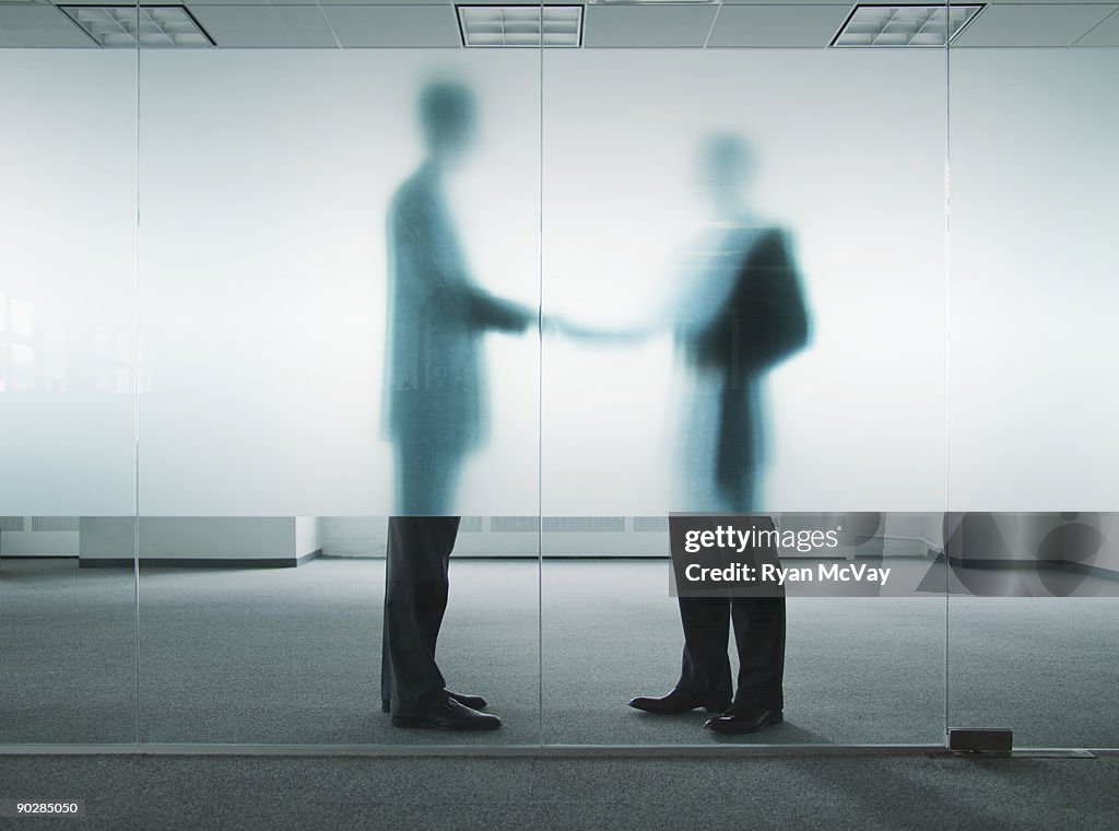 Silhouettes of business men shaking hands