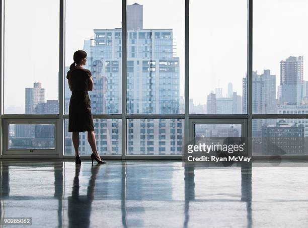 business woman looking out window - femme d'affaires photos et images de collection