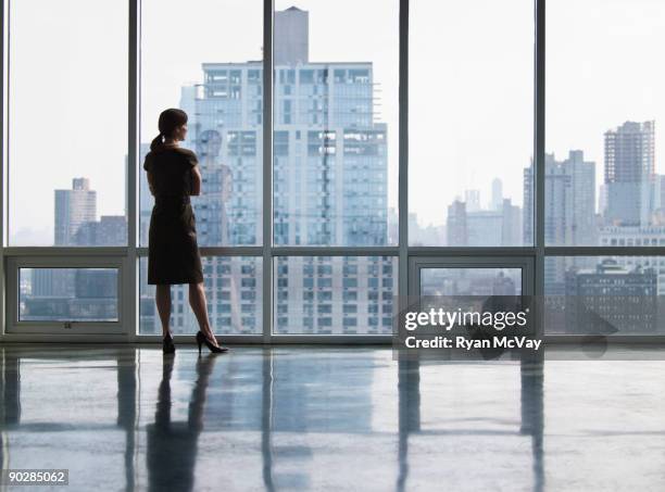 business woman looking out window - office building stockfoto's en -beelden