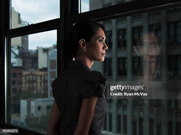 woman looking over city, reflected in window - business contemplation fotografías e imágenes de stock