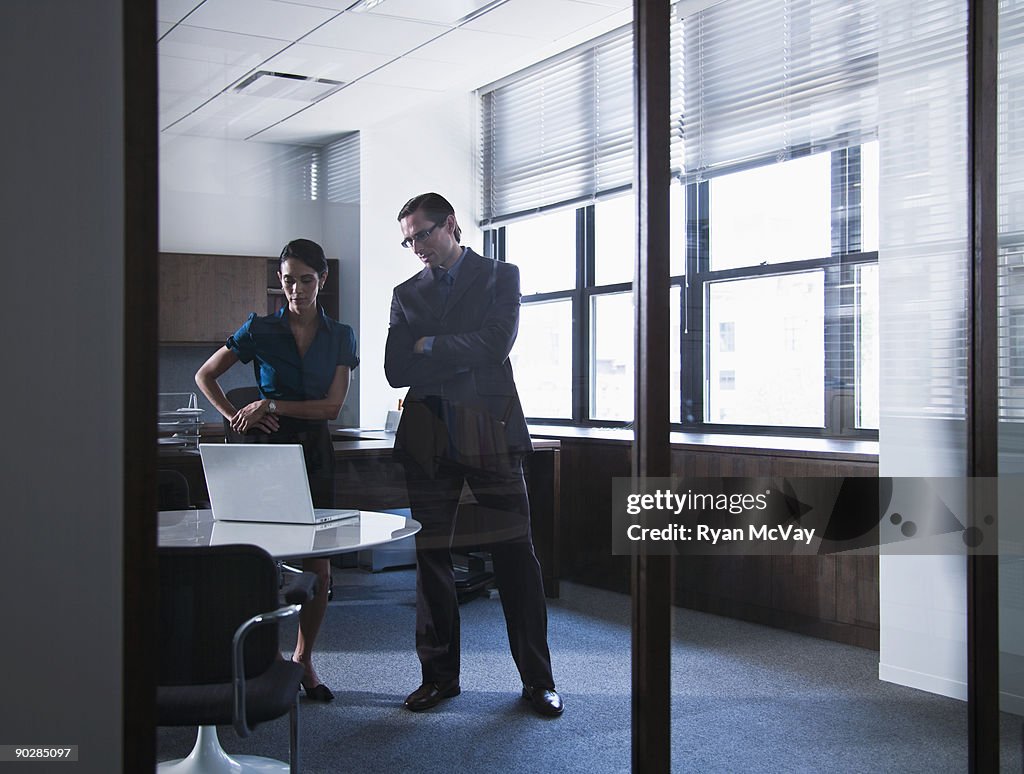 Coworkers looking at laptop in office