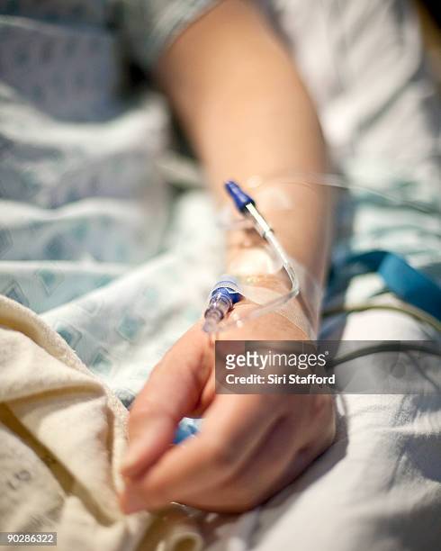 woman in hospital bed with iv in arm - iv infuus stockfoto's en -beelden