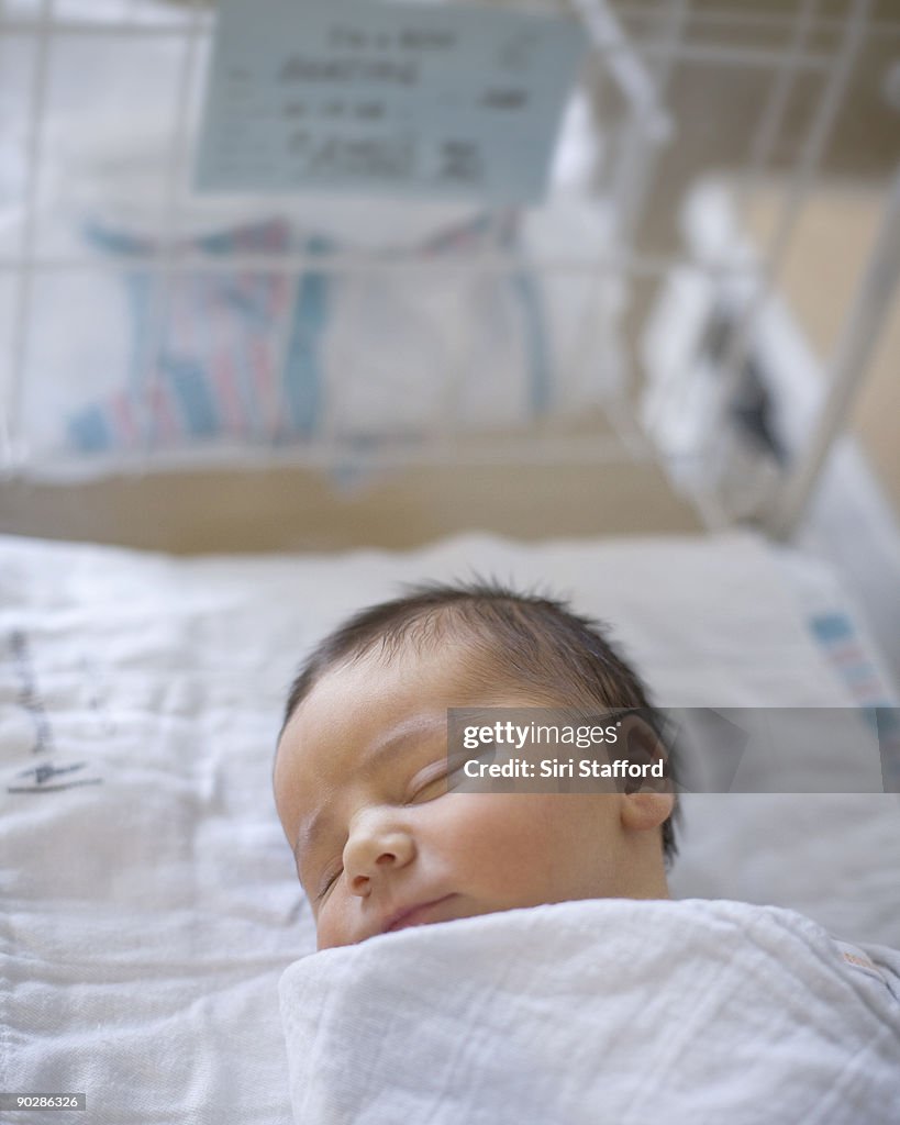 Newborn baby boy sleeping in hospital bassinet