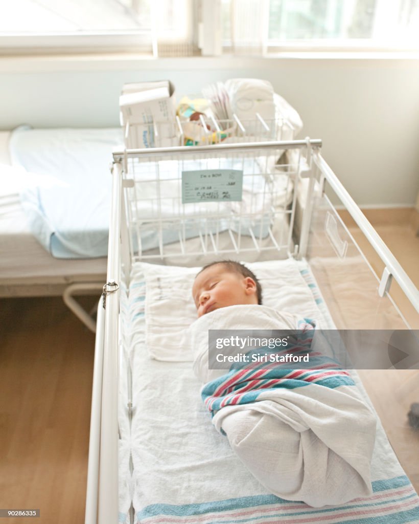 Newborn baby boy asleep in hospital bassinet