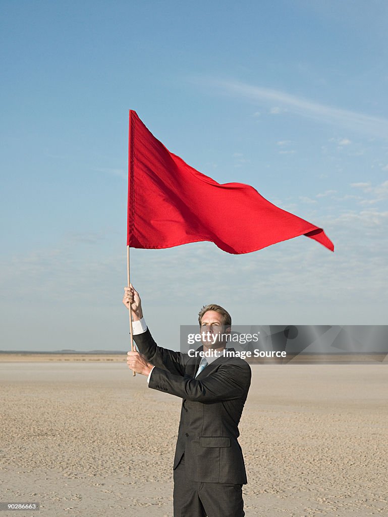 Businessman holding a red flag