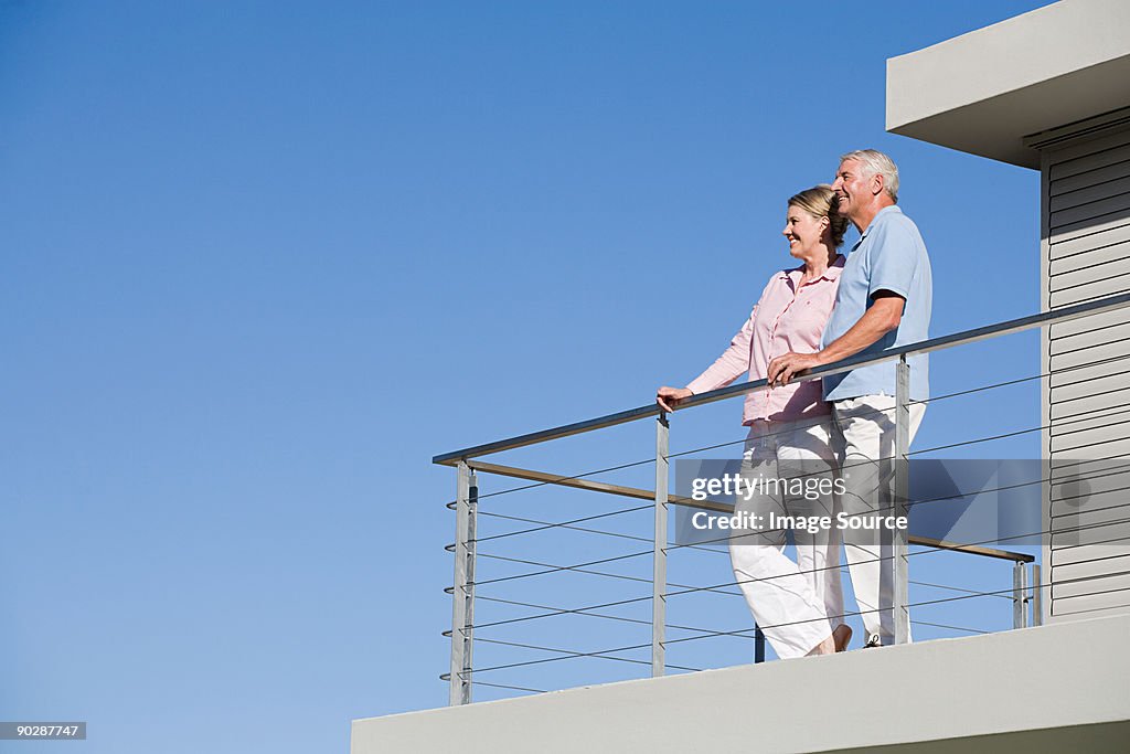 Couple standing on balcony of house