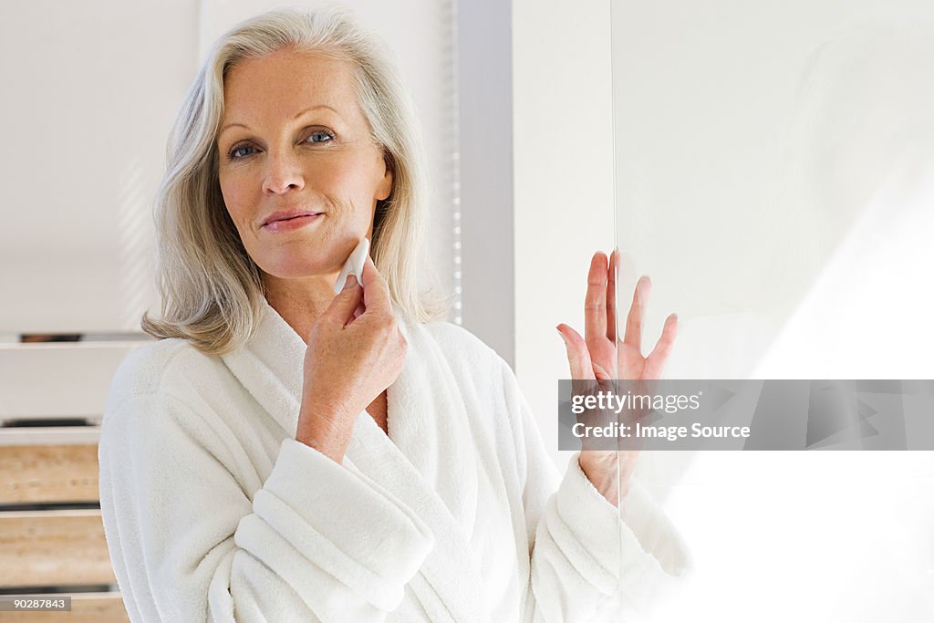 Middle aged woman cleansing face with cotton pad